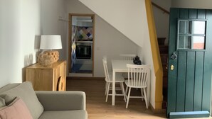 A cozy living room with a sofa, a table with chairs, and a kitchen area with a stove and oven. - Casa Carmo (Évora)