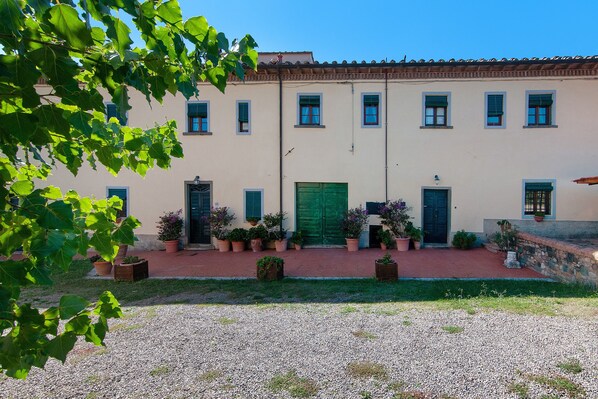 Um edifício com fachada simétrica, várias janelas com persianas e uma porta verde central.