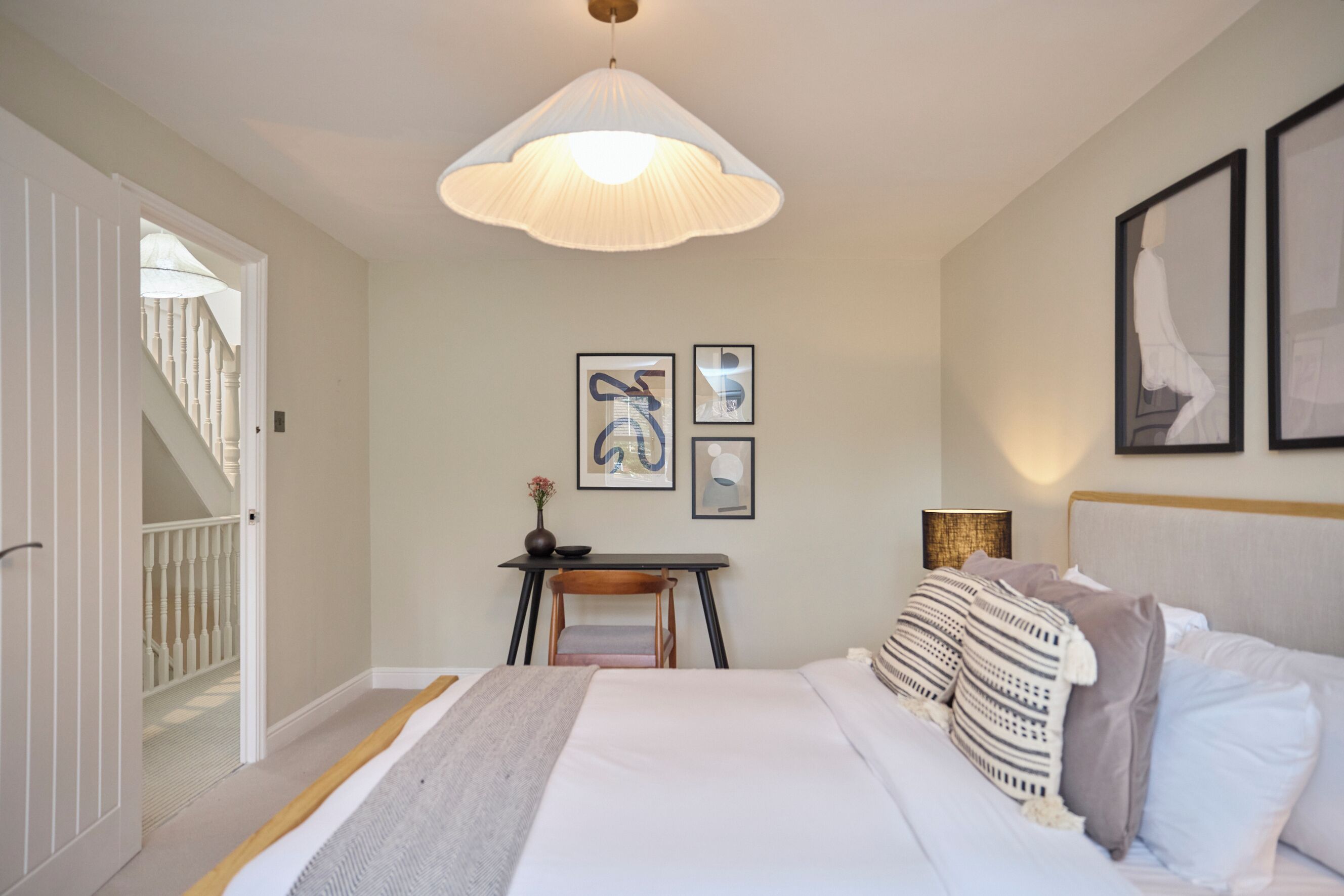 Une chambre avec un lit, un bureau et une chaise. Un escalier mène à une autre pièce.