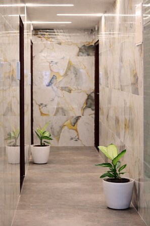 A hallway with marble walls and a polished floor, flanked by potted plants. - Axon Corporate Stays Whitefield Bengaluru (Bengaluru)