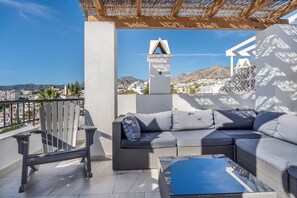 A balcony with a wicker sofa, a chair, and a glass coffee table. - Sea View Home with 3 Terraces near Burriana Beach (Nerja)