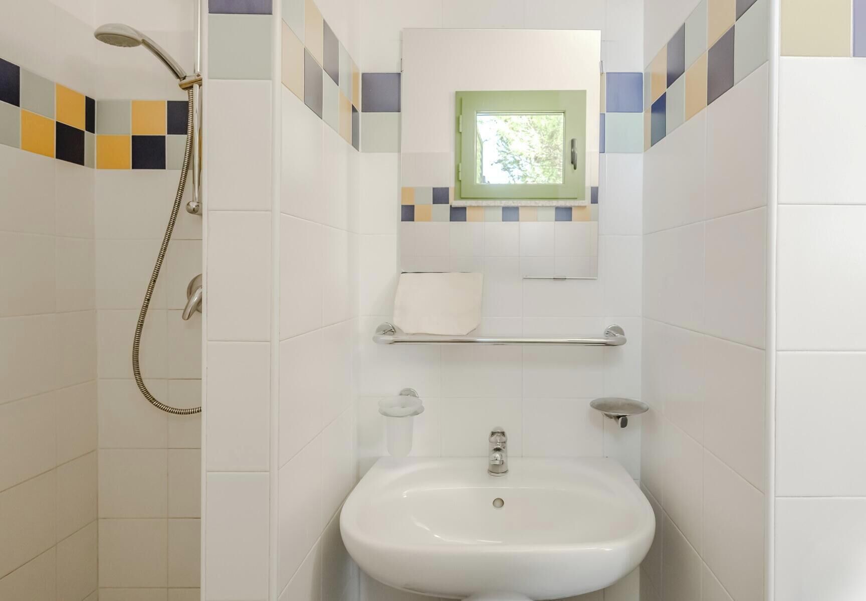 A bathroom with a shower, toilet, and sink, tiled with a geometric pattern.