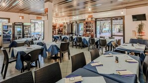 Ein Restaurant mit mehreren Tischen, Stühlen und einer Holzbalkenendecke.
