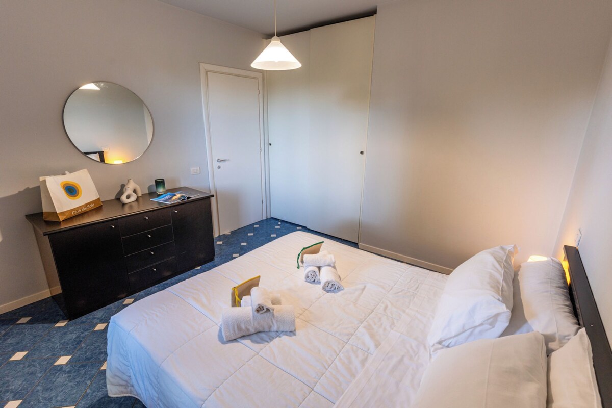 Ein Hotelzimmer mit Bett, Kommode, Spiegel und Pendelleuchte.