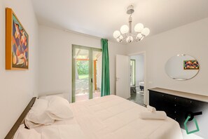 Une chambre à coucher avec un lit, une commode, un miroir et un tableau accroché au mur.
