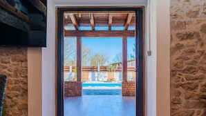A doorway leading to an outdoor patio with a pool, stone walls, and wooden beams. - Villa Niko ZadarVillas (Škabrnja)