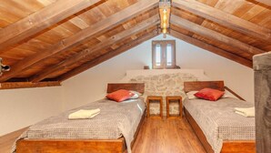 A bedroom with two wooden beds, stone walls, and a sloped ceiling with wooden beams. - Villa Niko ZadarVillas (Škabrnja)