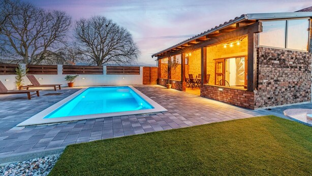 A modern outdoor pool area with a stone patio, a covered seating area, and a well-maintained lawn. - Villa Niko ZadarVillas (Škabrnja)