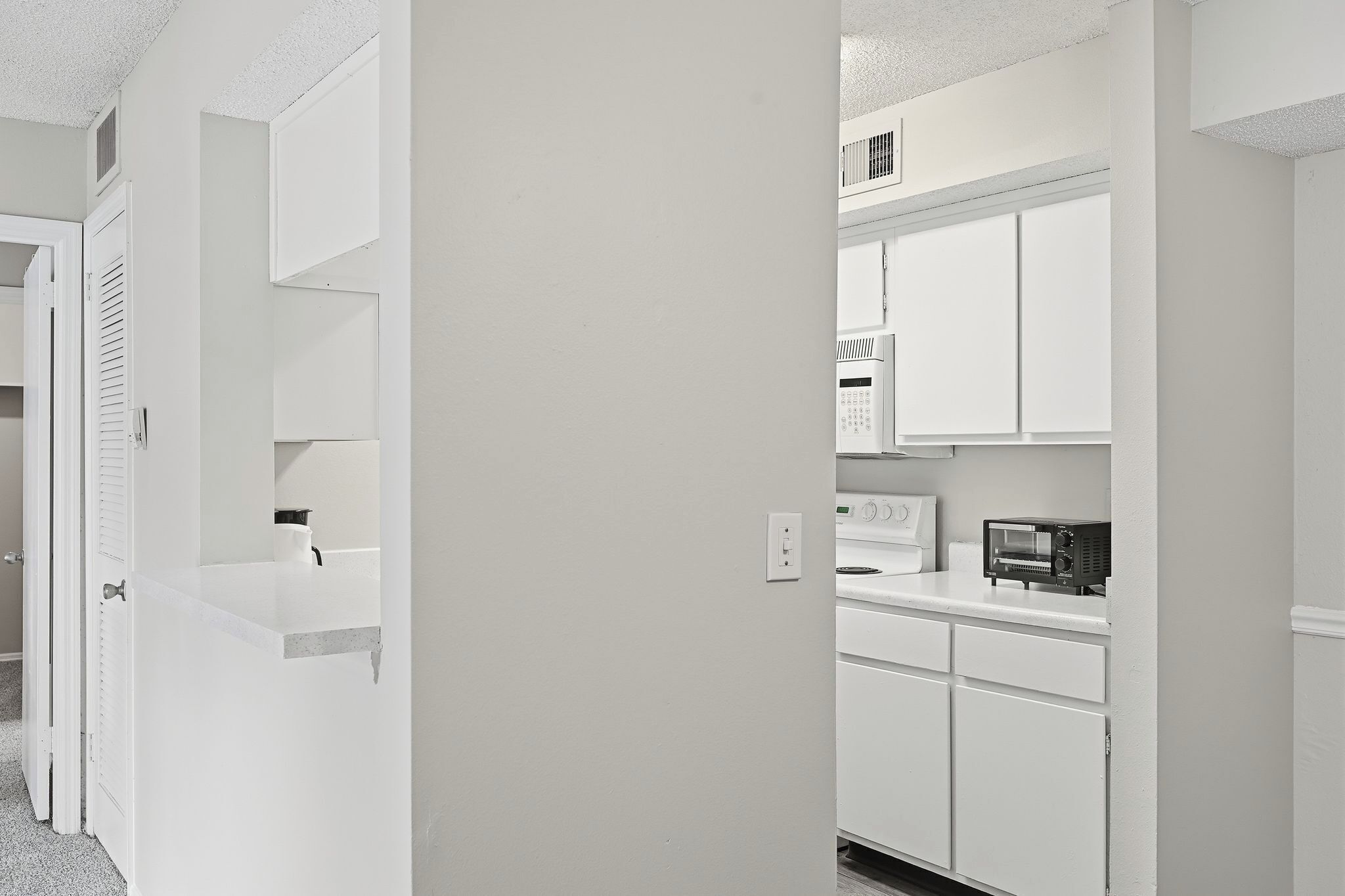 A modern kitchen with white cabinetry, a microwave, and a toaster.