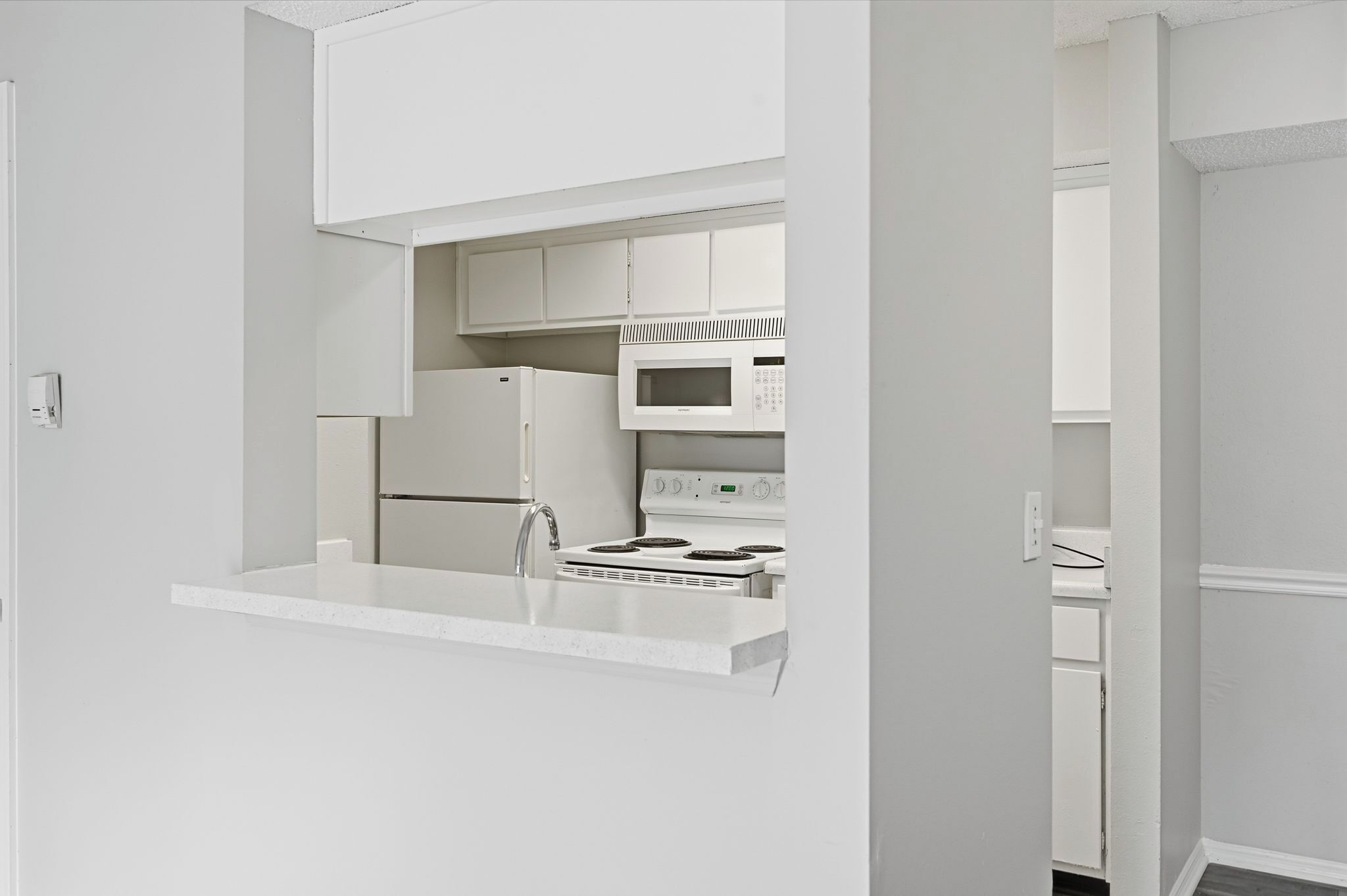 Una cocina moderna con armarios blancos, microondas integrado y estufa.