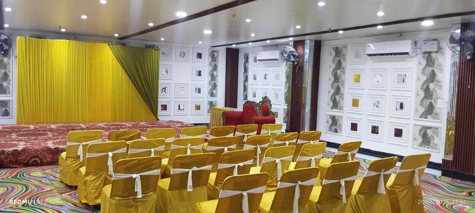 A conference room with rows of yellow chairs, a red sofa, and a stage with a microphone.