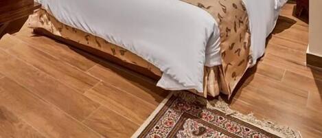 A hotel room with a large bed, a patterned rug, a wall tapestry, and a ceiling light fixture.
