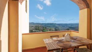 A balcony with a table set for two, a lantern, and a view of rolling hills. - Panorama – Apartment with Terrace and Views of the Tuscan Countryside (Montespertoli)