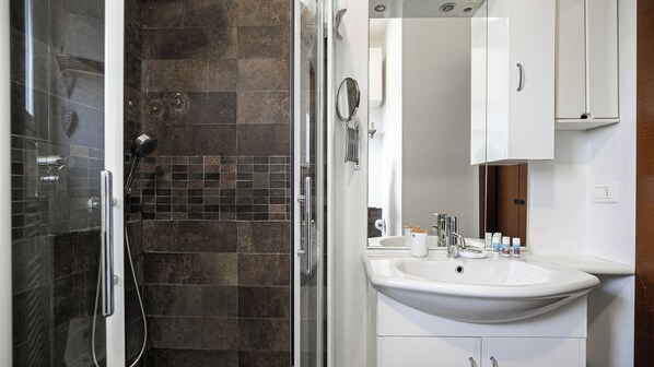 Un baño moderno con ducha vidriada, lavabo blanco y espejo.