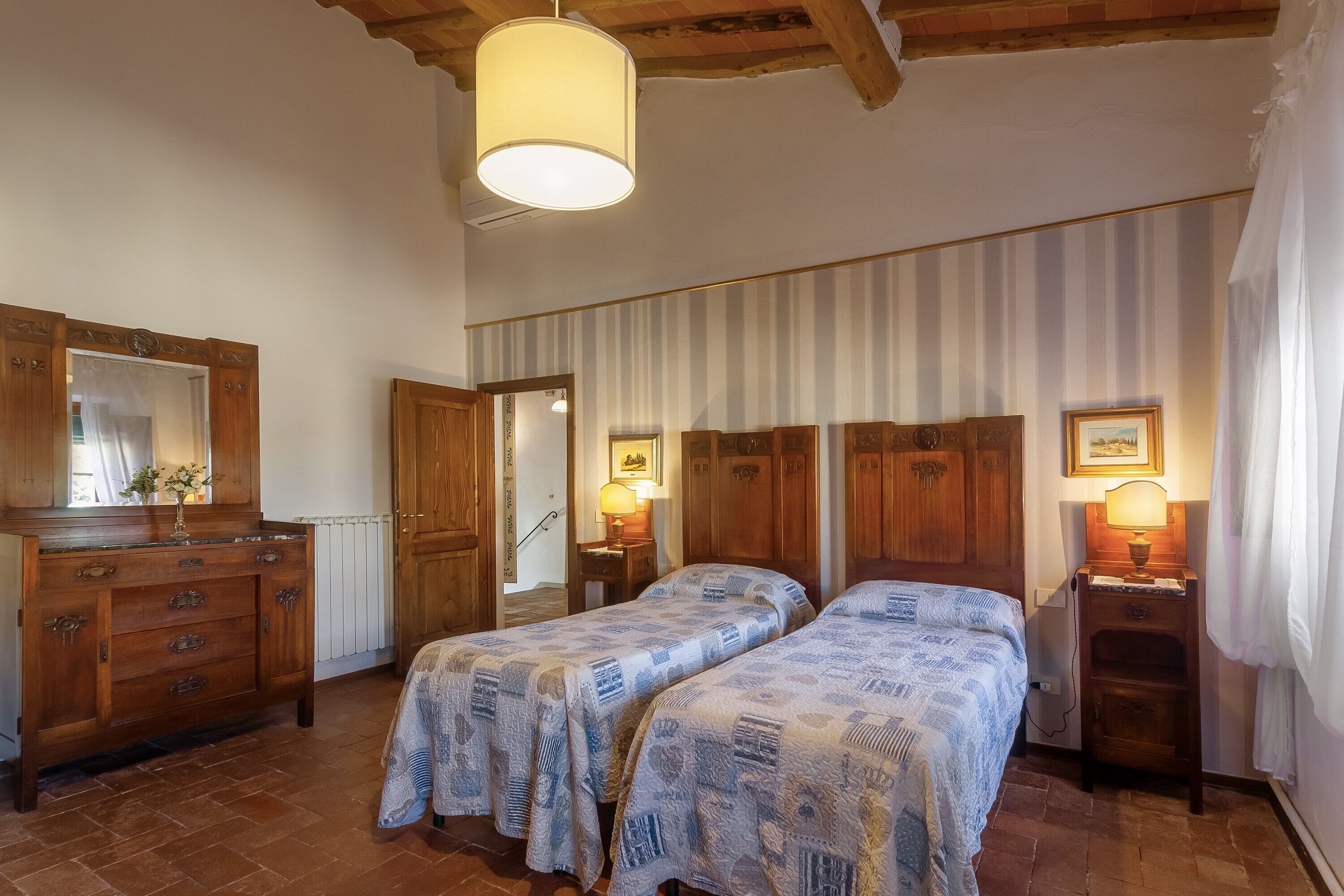 Un dormitorio con dos camas, muebles de madera, un aparador y un espejo.