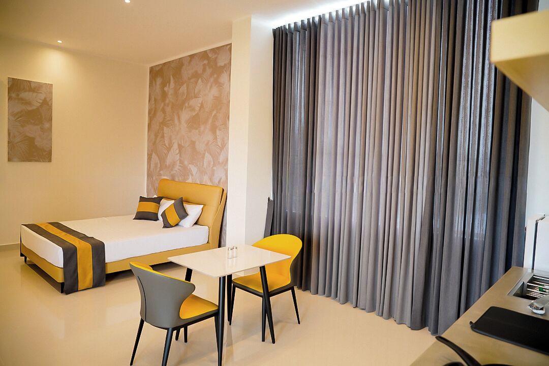 Une chambre d’hôtel avec un lit, un bureau, une chaise et un rideau.