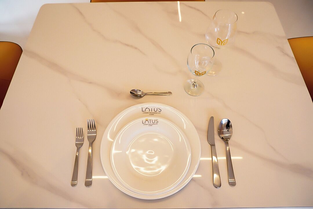 A table set with a white plate, cutlery, and two glasses on a marble table.