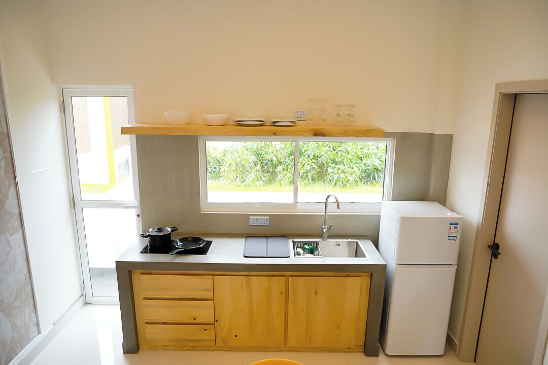 A small kitchen with a window, a sink, a stove, and a refrigerator.