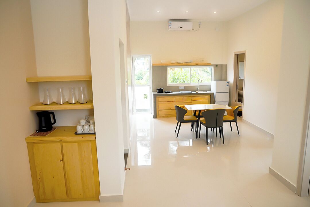 A modern kitchen with a dining area, featuring a central island, built-in cabinets, and a large window providing natural light.