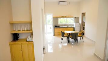 A modern kitchen with a dining area, featuring a central island, built-in cabinets, and a large window providing natural light.