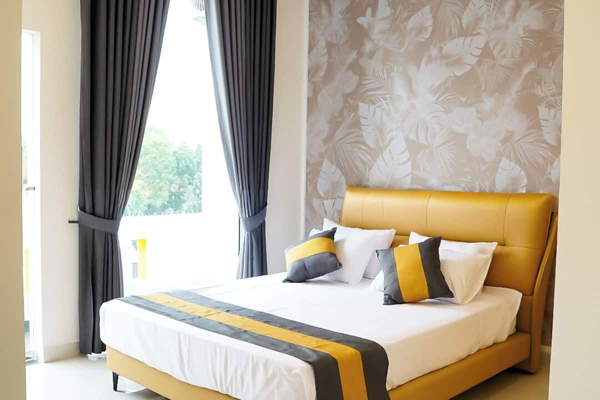 A modern bedroom with a large bed, a headboard, and a floral wallpaper.