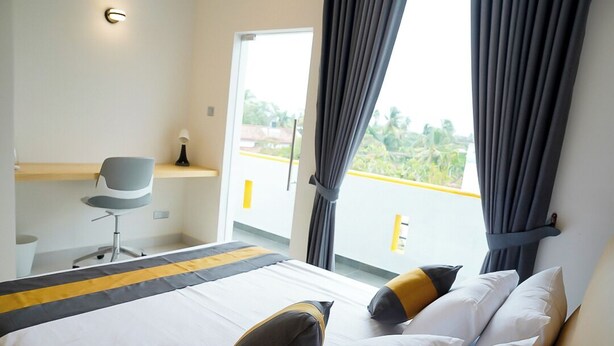 Une chambre d’hôtel équipée d’un lit, d’un bureau, d’une chaise et offrant une vue sur l’extérieur.