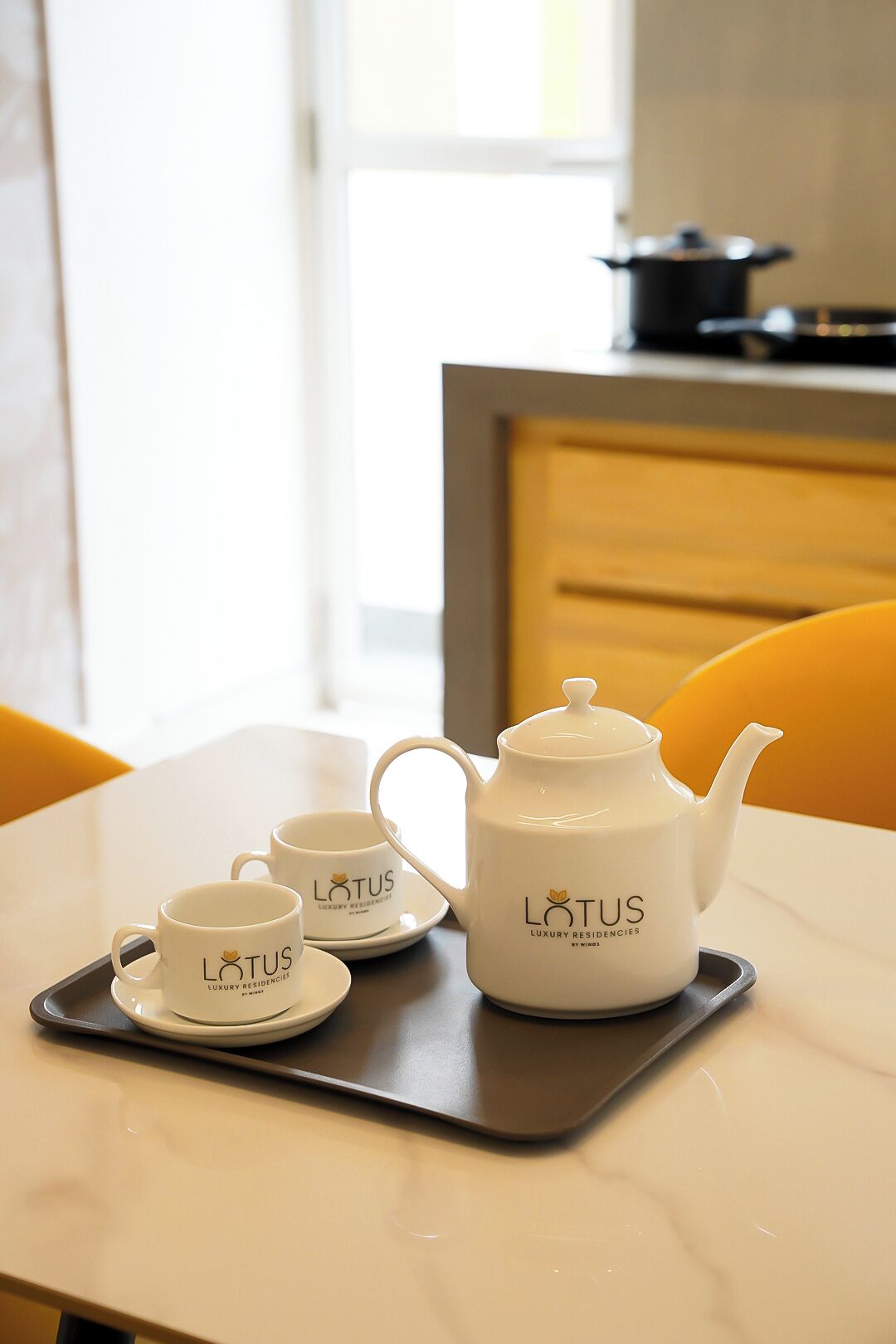 A table with a teapot and two cups labeled "LOTUS LUXURY RESIDENCIES BY MIKE" on a tray.