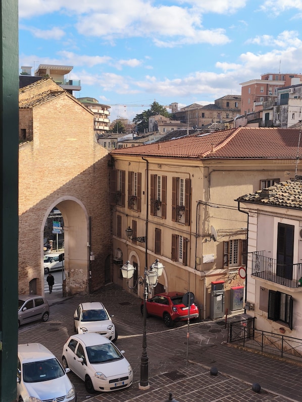 A street view with a brick building, parked cars, and a clear sky.