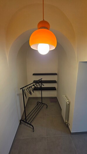 Un corridoio con uno stendibiancheria in metallo nero, un termosifone e una lampada a soffitto.