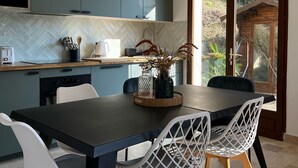 Una cocina moderna con comedor, que cuenta con un ventanal grande, horno empotrado y una mesa con sillas.