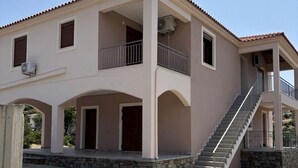 A two-story house with a covered patio, a staircase, and a stone foundation.