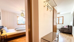 Ein modernes Zimmer mit Holzboden, einem Bett mit karierter Bettwäsche, einer Couch und einem Tisch mit einem Metallgestell.