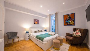 Una camera da letto moderna con un letto grande, lampade da comodino, una poltrona, un divano e opere d'arte alle pareti.