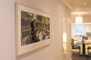 A framed abstract painting on a wall in a hallway. - Beautifully renovated 2-bedroom, 2-bathroom garden apartment in the heart of Kensington & Chelsea, featuring a spacious king en-suite, flexible bedding, bright living areas, and elegant finishes — perfect for families, friends, or business stays. (Greater London)
