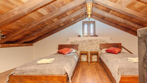 A bedroom with two wooden beds, stone walls, and a sloped ceiling with wooden beams. - Villa Niko Zadarvillas (Škabrnja)