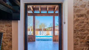 A doorway leading to an outdoor patio with a pool, stone walls, and wooden beams. - Villa Niko Zadarvillas (Škabrnja)