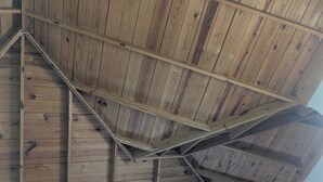 Una habitación con techo de madera inclinado y unidad de aire acondicionado integrada.