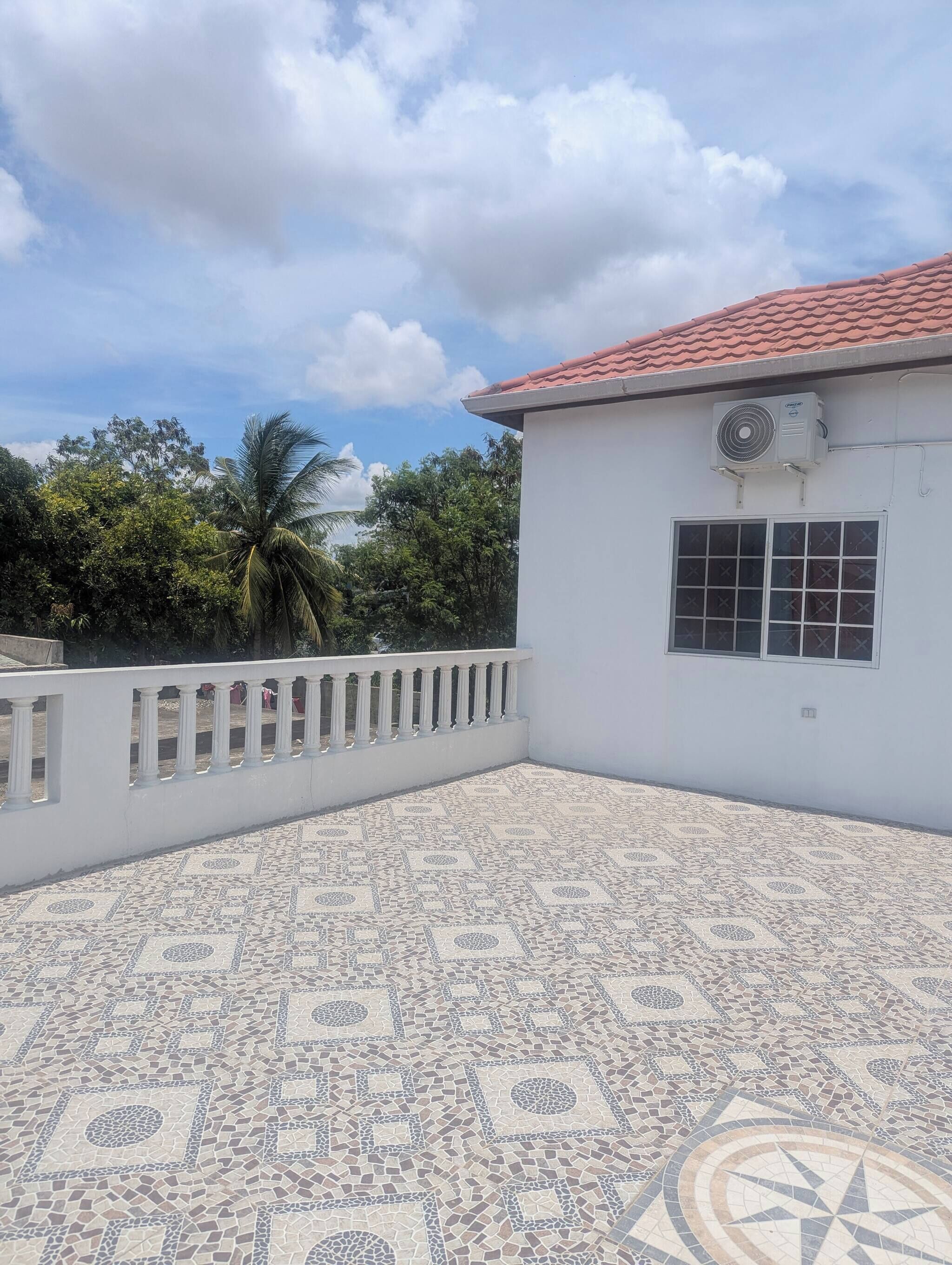 A building with a tiled patio, a white exterior, and a red-tiled roof.