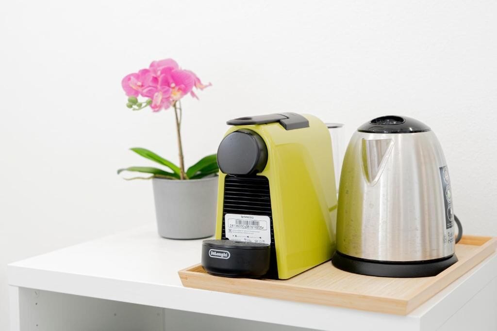 A kitchen counter with a coffee maker, a kettle, and a small appliance on a tray.