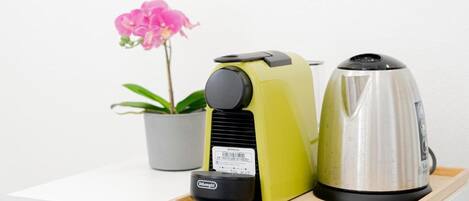 A kitchen counter with a coffee maker, a kettle, and a small appliance on a tray.