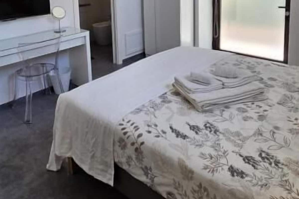 Een slaapkamer met een bed, een bureau en een kledingkast.
