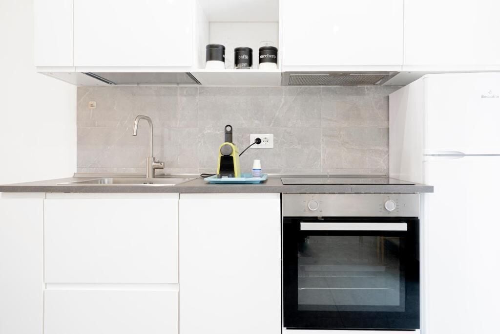 A modern kitchen with a built-in oven, a sink, and a coffee machine.