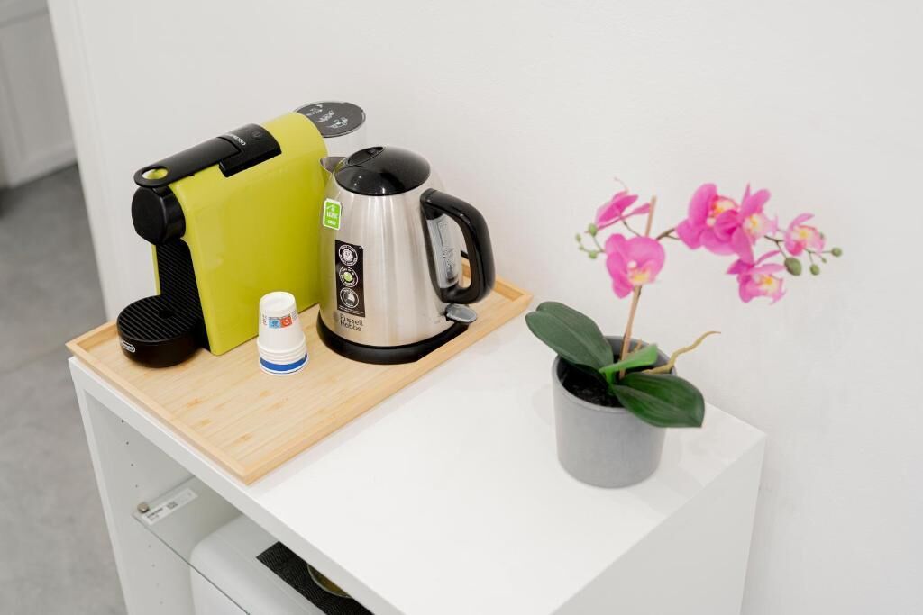 A kitchen counter with a coffee maker, a kettle, and a small potted plant.