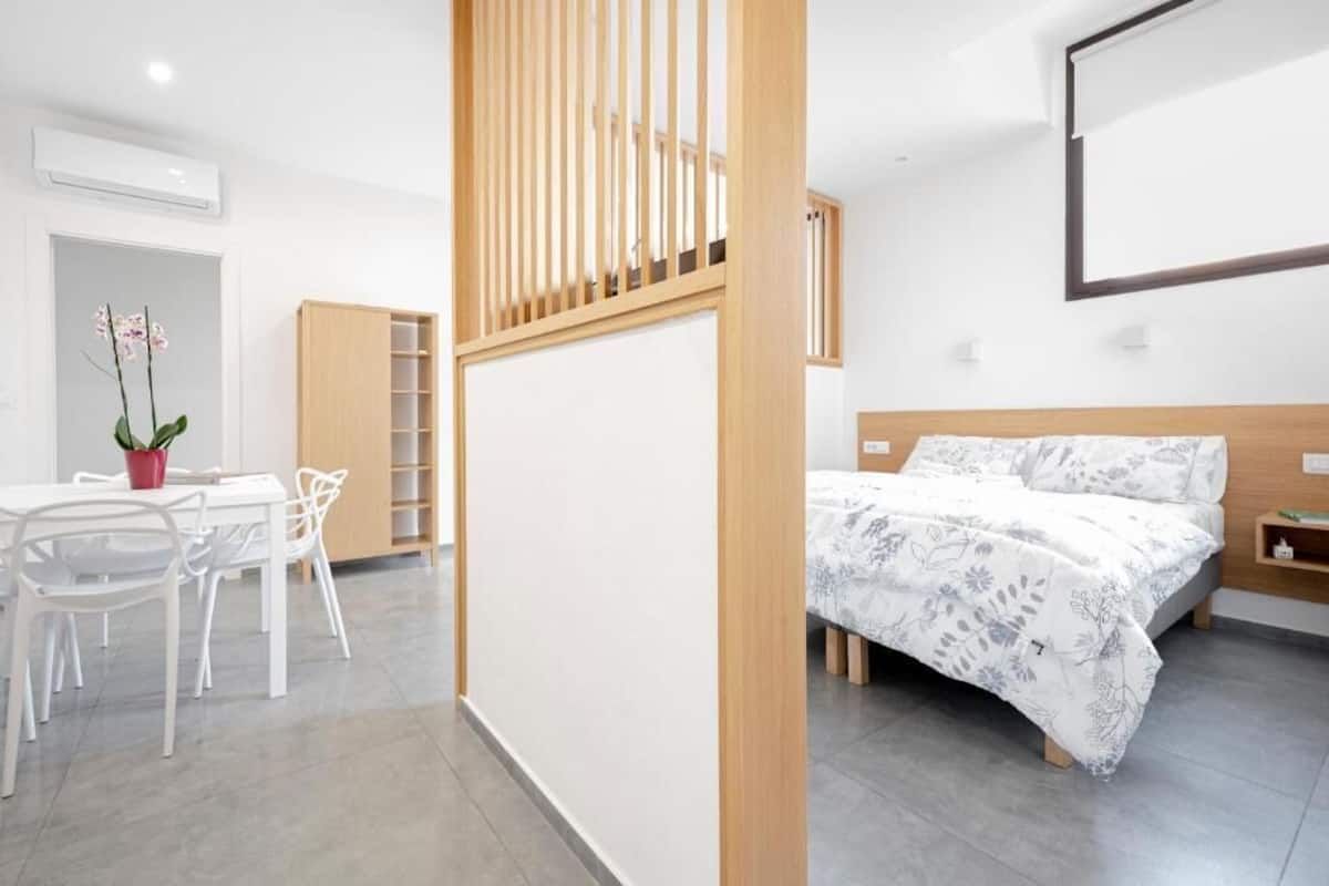 Een moderne slaapkamer met een houten bed, een witte nachtkastje en een inbouwkast.