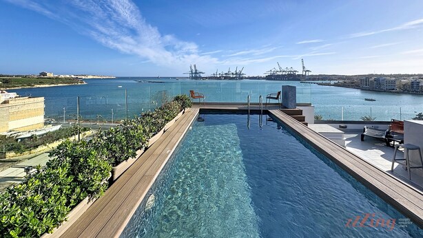 A rooftop infinity pool with a clear view of the sea and port in the background.