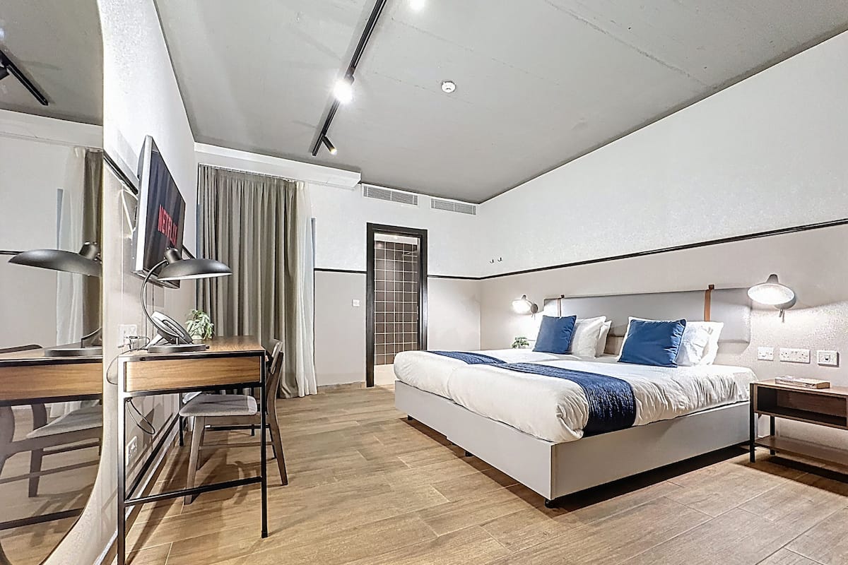 Een moderne hotelkamer met een bed, bureau en stoel, een televisie en een deur.