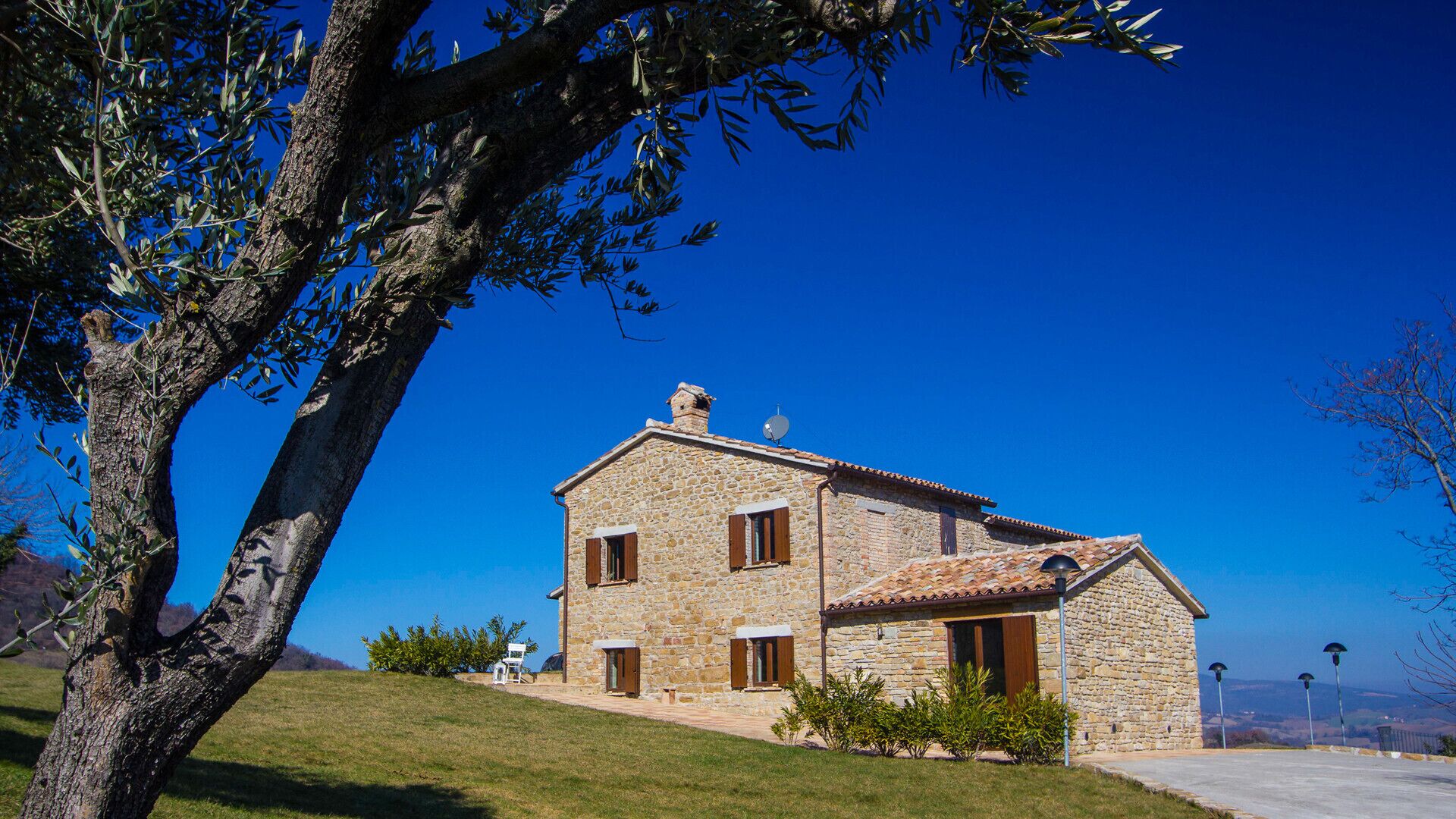 A stone house with a sloped roof, a chimney, and a satellite dish.