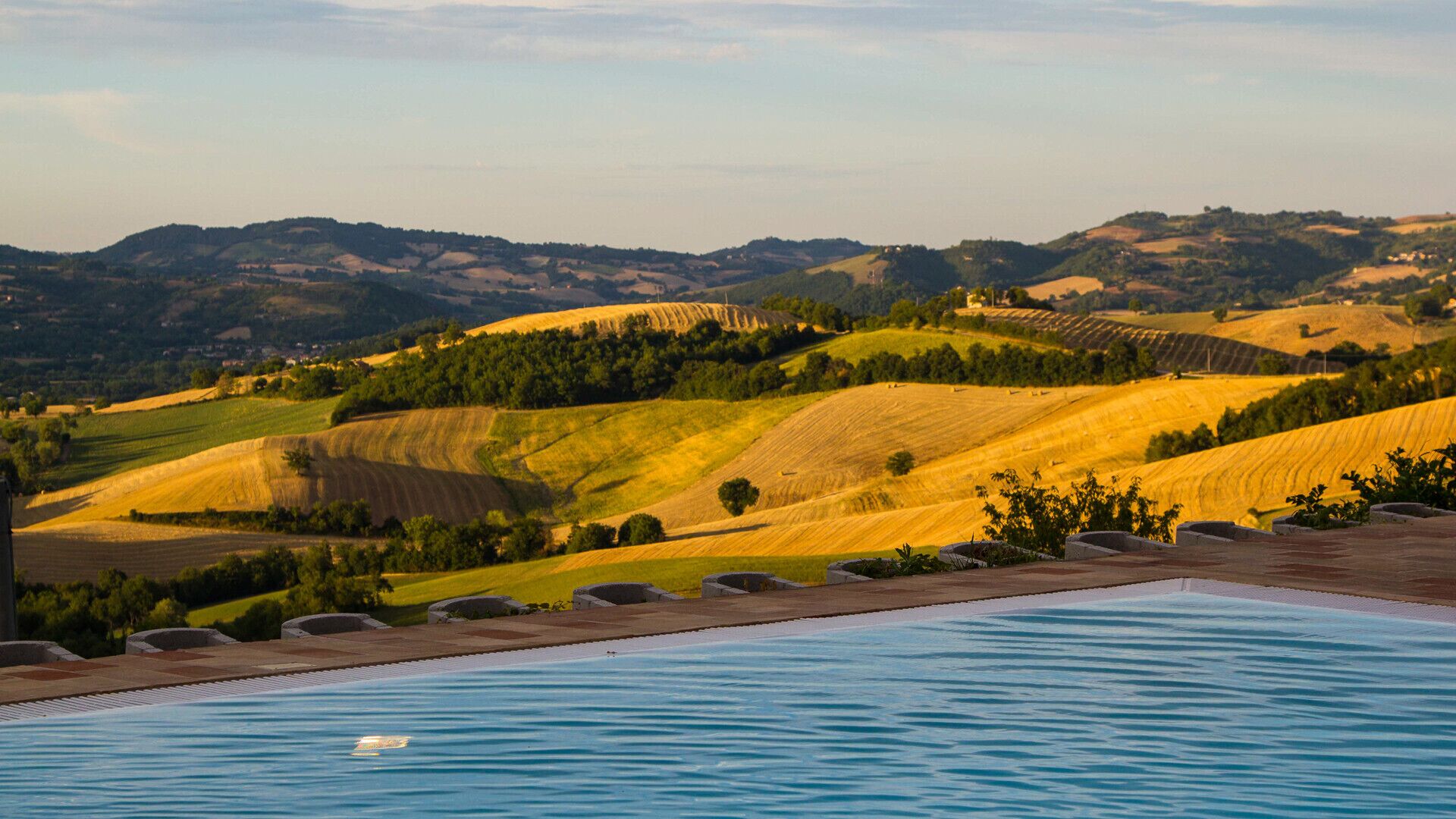 A pool with a view of rolling hills and fields.