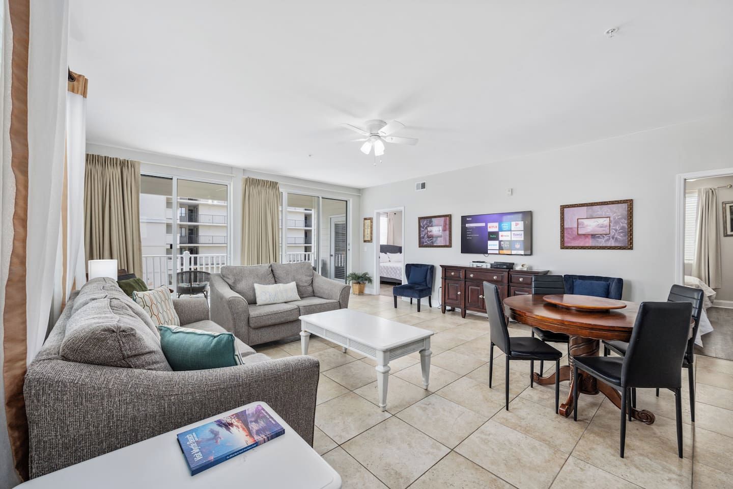 Uma sala de estar ampla com sofá, mesa de centro e área de jantar com cadeiras e mesa de madeira.