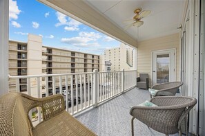 A balcony with wicker furniture, a ceiling fan, and a view of adjacent buildings. - Ocean Breeze Villas-5 bd /5.5 bath-Sleeps 18-(9 BEDS)-Parking-WIFI-Pool (North Myrtle Beach)